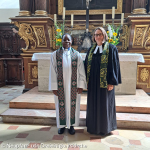 Pastor John Mwasakilali und Pfarrerin Marjaana Marttunen vor dem Altar der Dreieinigkeitskirche.